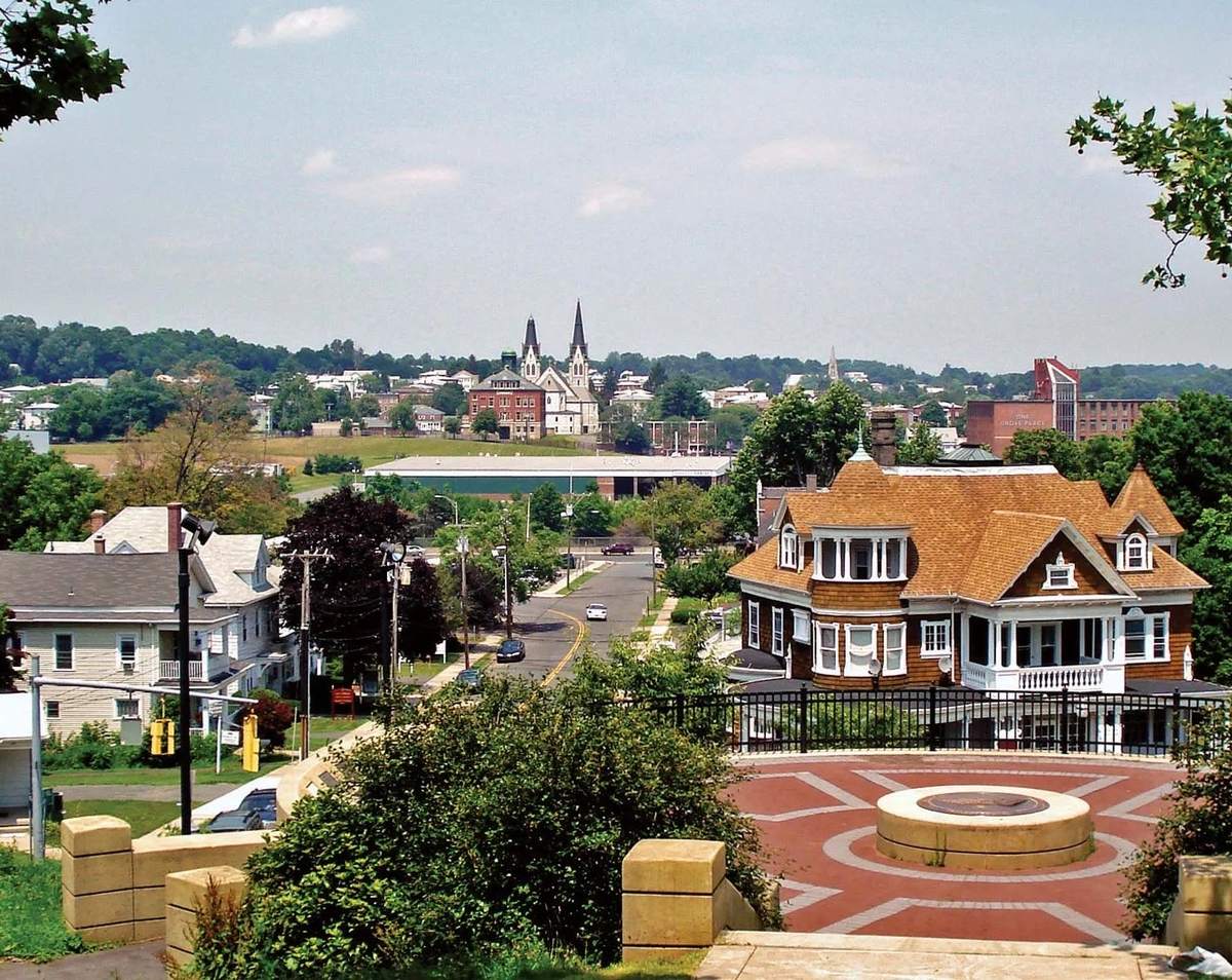 View over New Britain from Walnut Hill Park: a shingled Victorian house in the foreground, twin church spires and the city beyond